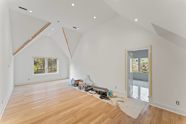 unfurnished living room with light hardwood / wood-style floors, high vaulted ceiling, and a wealth of natural light