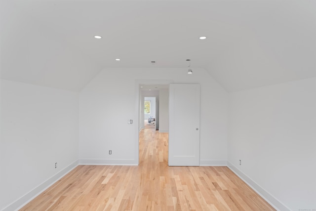 additional living space featuring vaulted ceiling and light wood-type flooring