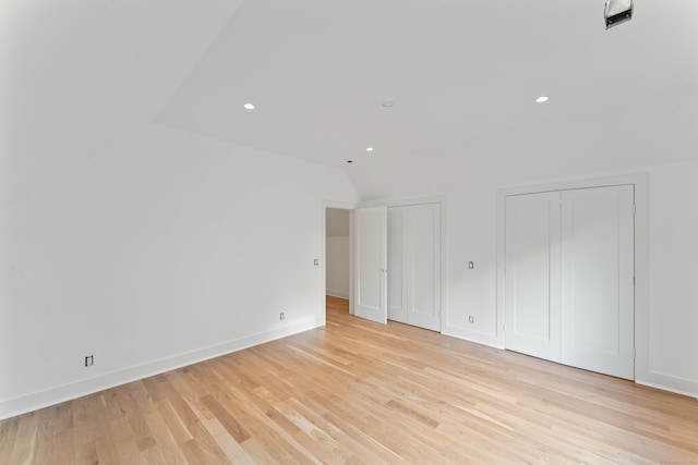 spare room featuring lofted ceiling and light wood-type flooring