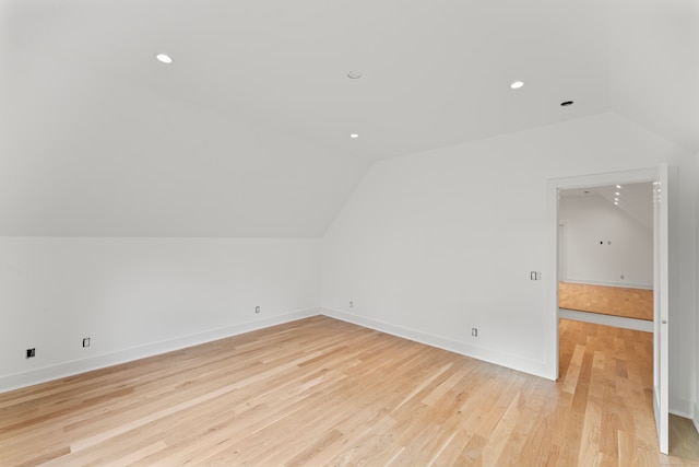 additional living space featuring vaulted ceiling and light wood-type flooring