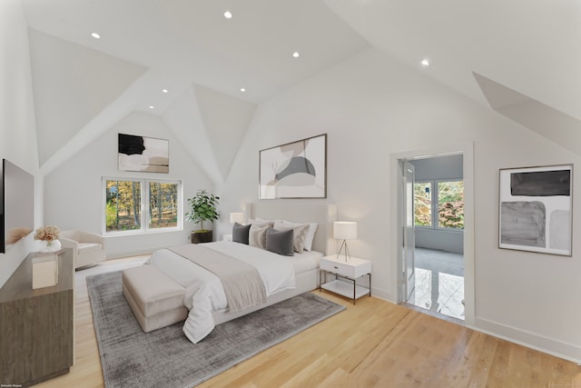 bedroom with high vaulted ceiling, multiple windows, and light hardwood / wood-style floors