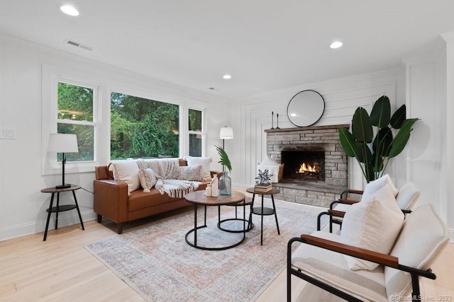 living room with a fireplace, light wood-type flooring, and crown molding