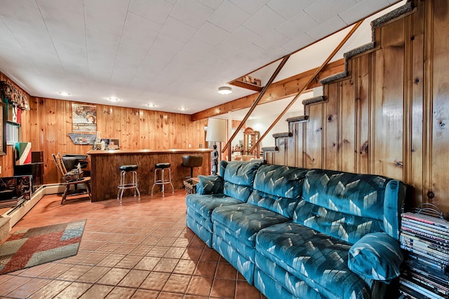 living room with bar, wooden walls, and tile patterned floors