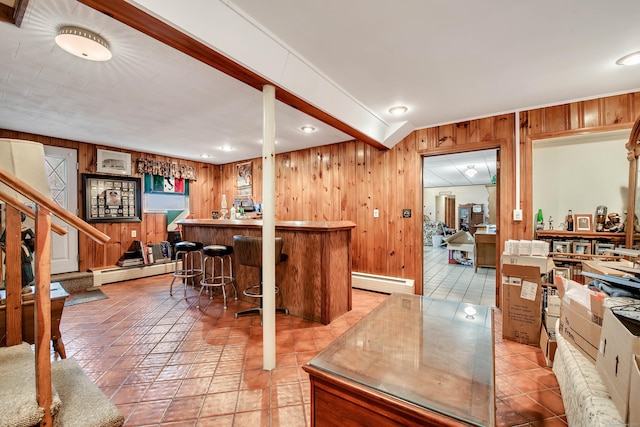 kitchen with light tile patterned floors, a breakfast bar area, a baseboard radiator, kitchen peninsula, and wood walls