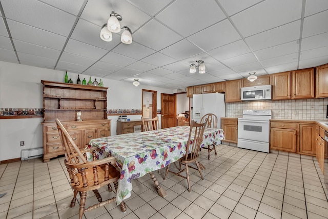 tiled dining area with a drop ceiling and a baseboard radiator