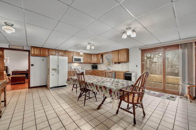 tiled dining space with sink and a paneled ceiling