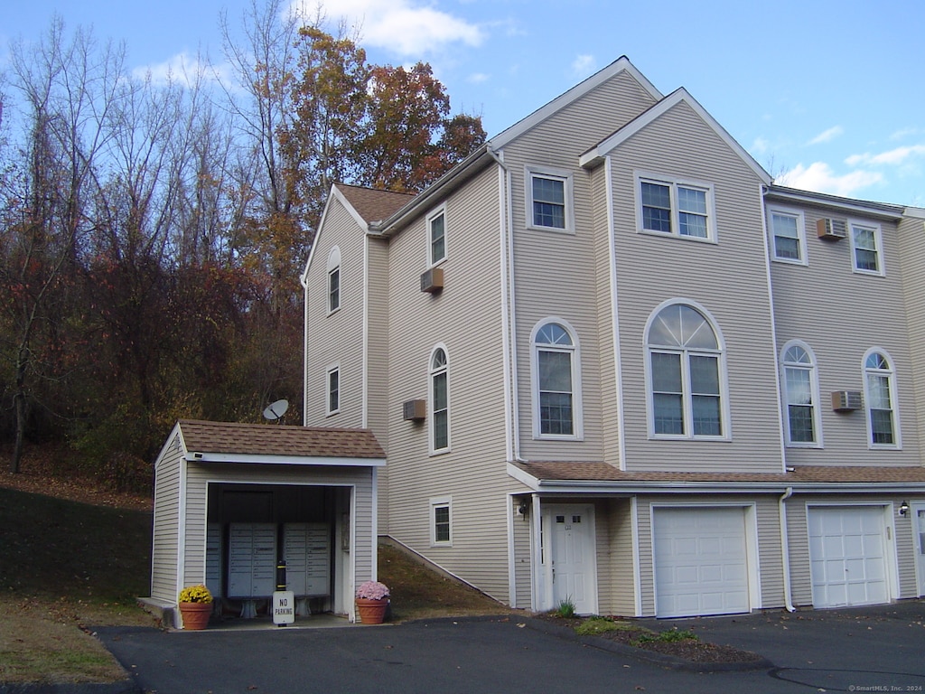 view of front of property with a garage and a wall unit AC