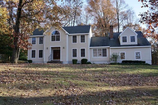 view of front of property featuring entry steps, a chimney, and a front yard