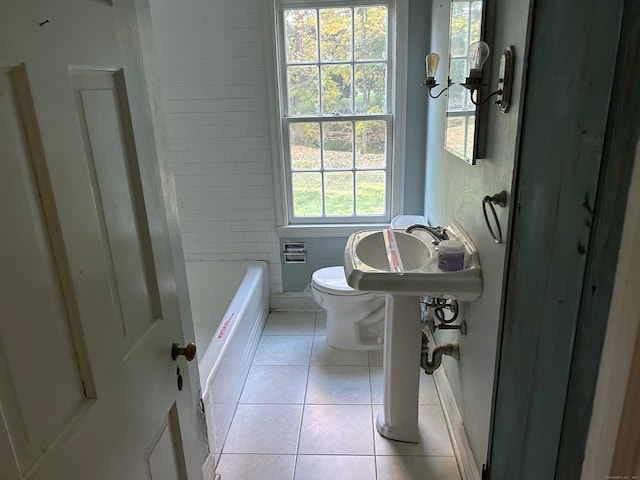 bathroom with a bathtub, toilet, tile patterned floors, and a wealth of natural light