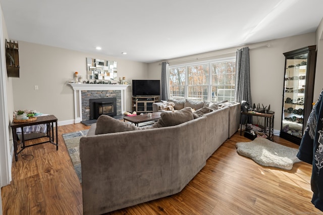 living room with a stone fireplace and light wood-type flooring