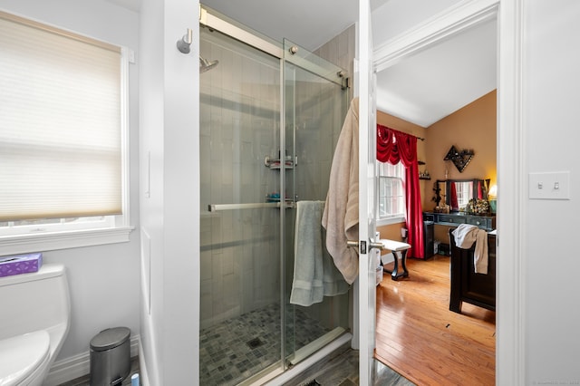 bathroom with a shower with door, toilet, and hardwood / wood-style floors