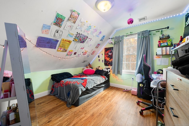 bedroom with wood-type flooring and vaulted ceiling