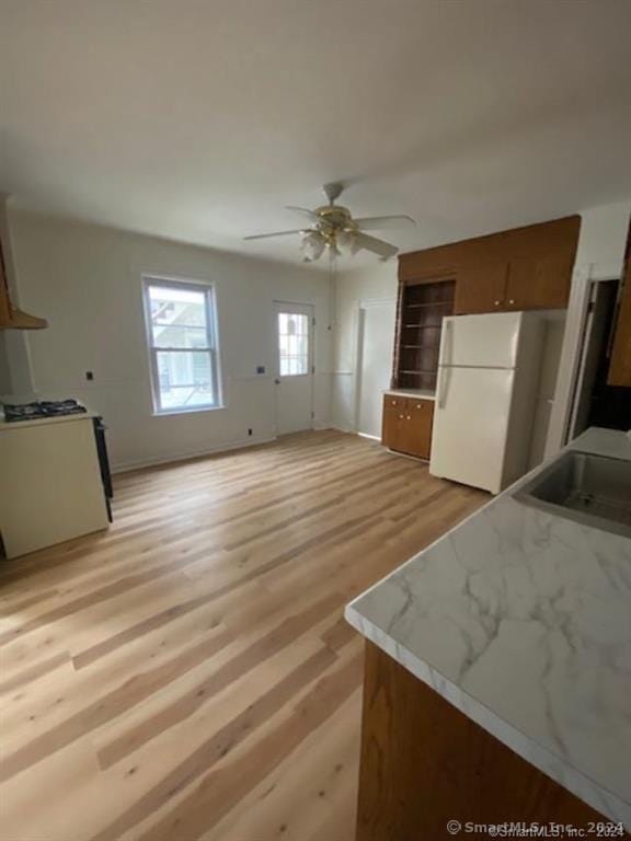 kitchen featuring light hardwood / wood-style flooring, white fridge, sink, and ceiling fan