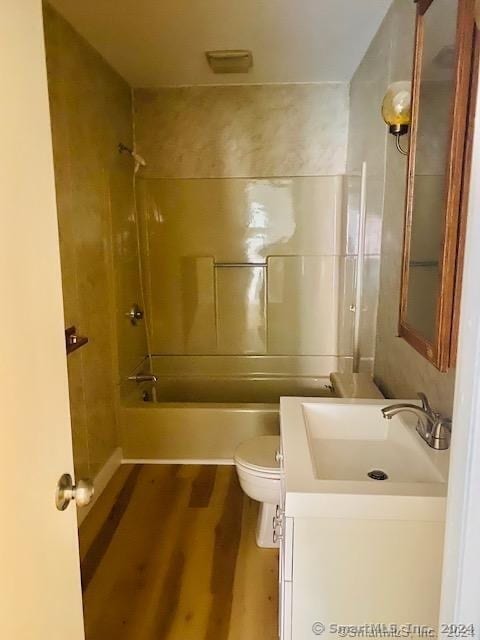 full bathroom with vanity, toilet, tiled shower / bath combo, and hardwood / wood-style floors