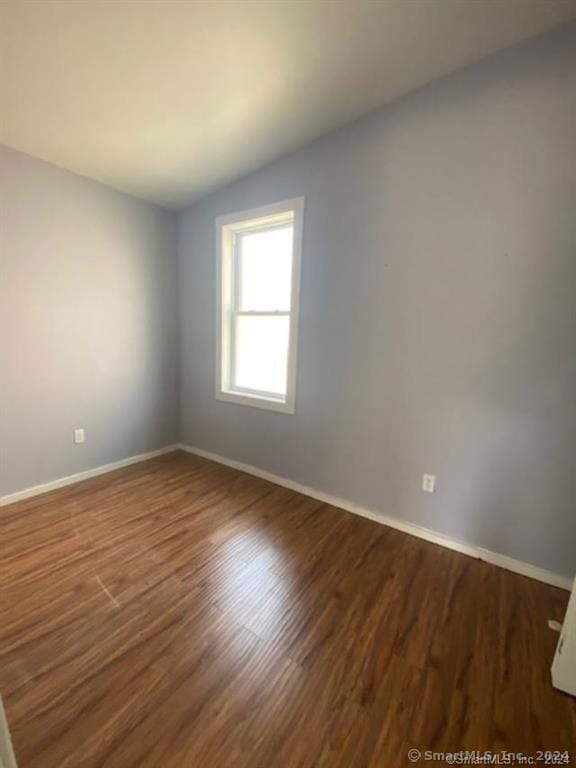 empty room featuring dark wood-type flooring and lofted ceiling