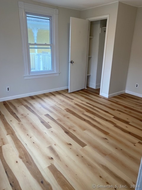 unfurnished bedroom with a closet and light wood-type flooring