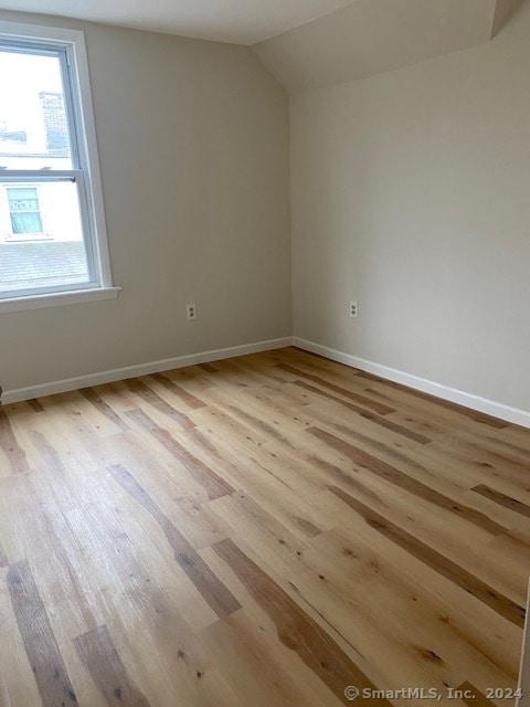 spare room with lofted ceiling and light hardwood / wood-style floors