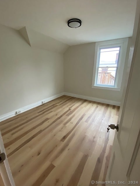 additional living space with light hardwood / wood-style floors and vaulted ceiling