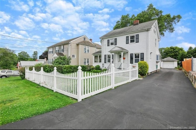 view of front of property with a front yard, a garage, and an outdoor structure