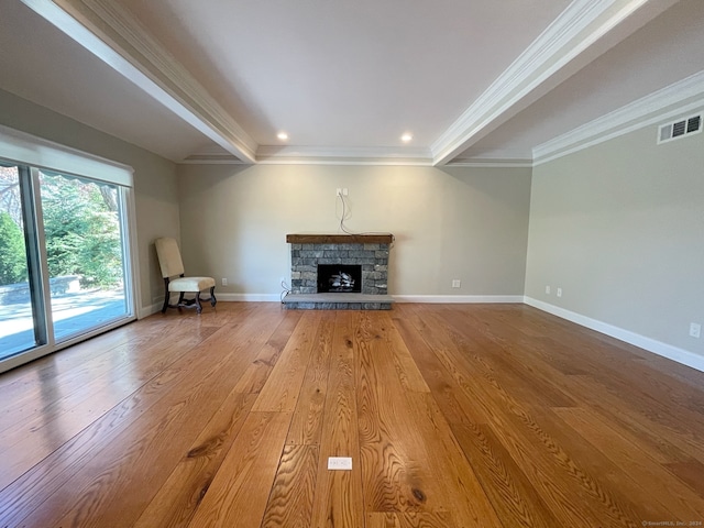 unfurnished living room featuring crown molding, a stone fireplace, and wood-type flooring