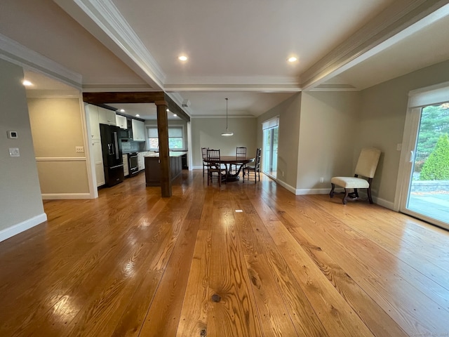 interior space with beam ceiling, ornamental molding, decorative columns, and light hardwood / wood-style floors