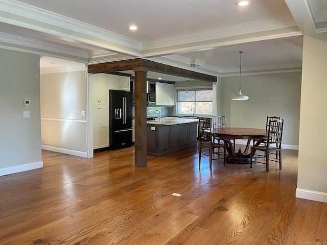 kitchen featuring white cabinets, black refrigerator with ice dispenser, dark wood-style flooring, and baseboards