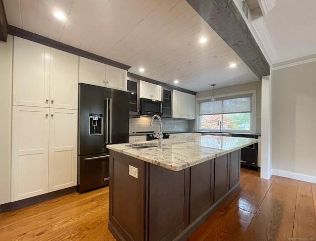 kitchen with light wood-style floors, black appliances, recessed lighting, light stone countertops, and a kitchen island with sink