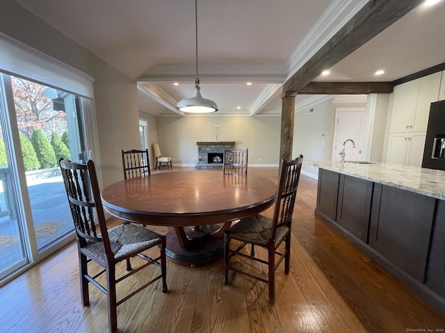 dining space with baseboards, wood finished floors, a fireplace, and crown molding