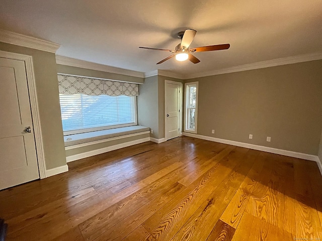 spare room with ornamental molding, a ceiling fan, wood finished floors, and baseboards