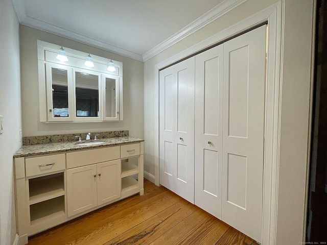 bathroom with wood finished floors, vanity, crown molding, and baseboards