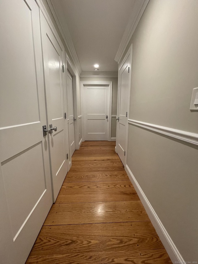 corridor with crown molding and light wood-style flooring