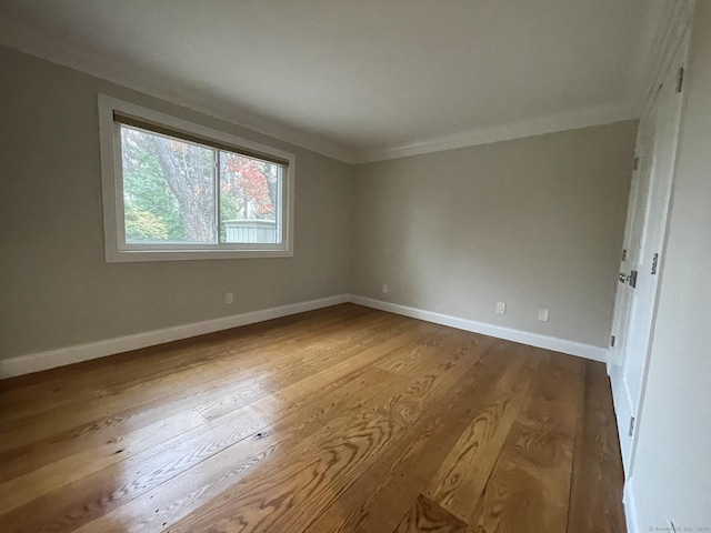 spare room featuring dark wood-style flooring, crown molding, and baseboards