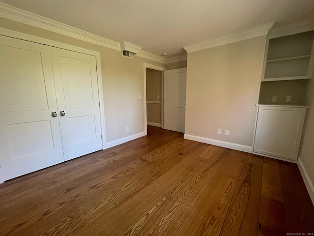 unfurnished bedroom featuring baseboards, visible vents, wood finished floors, and crown molding