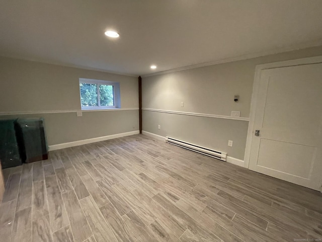 basement with baseboards, light wood-type flooring, recessed lighting, and a baseboard radiator