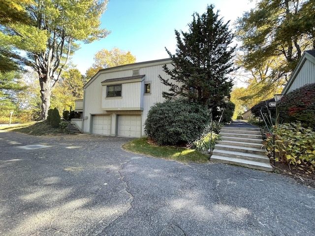 view of property exterior featuring driveway, stairway, and an attached garage