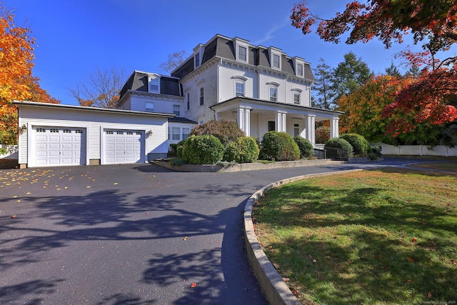 view of front of house with covered porch, a front lawn, and a garage