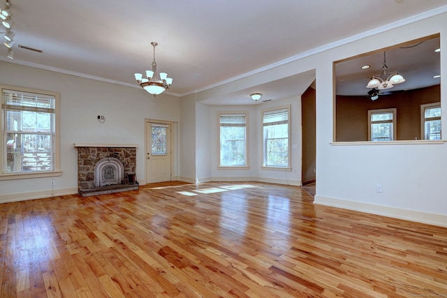 unfurnished living room with light hardwood / wood-style flooring, an inviting chandelier, a fireplace, and crown molding