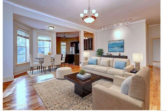 living room featuring light hardwood / wood-style flooring, ornamental molding, ceiling fan with notable chandelier, and rail lighting