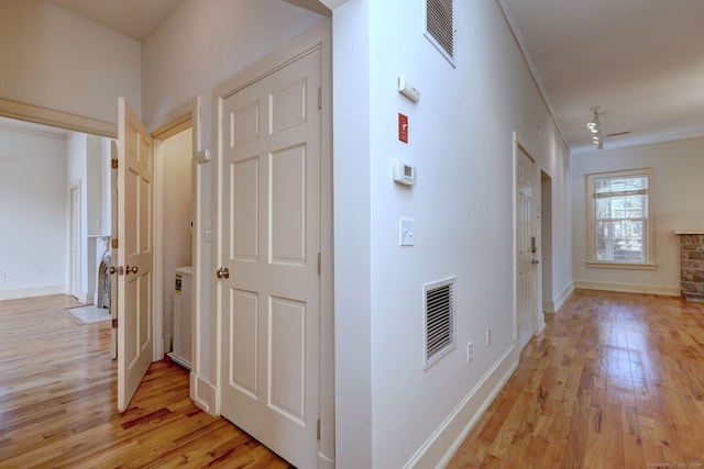 hallway with crown molding and light wood-type flooring