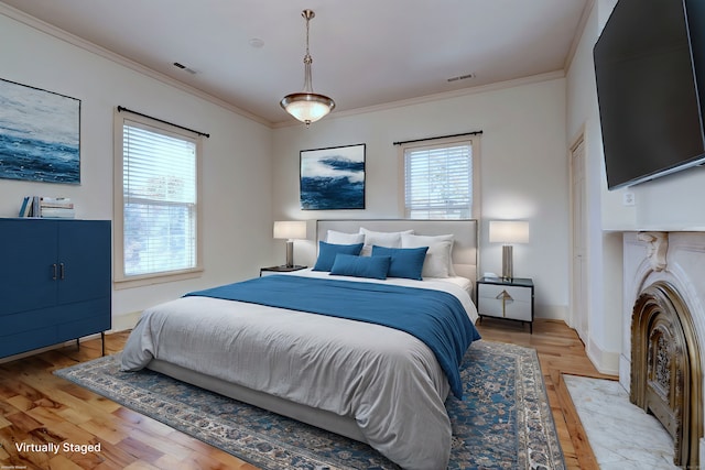 bedroom with multiple windows, light wood-type flooring, and crown molding