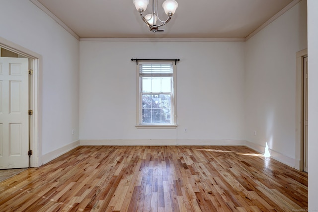 empty room with ornamental molding, an inviting chandelier, and light wood-type flooring