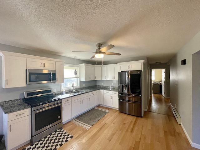 kitchen with sink, light wood-type flooring, baseboard heating, white cabinetry, and stainless steel appliances