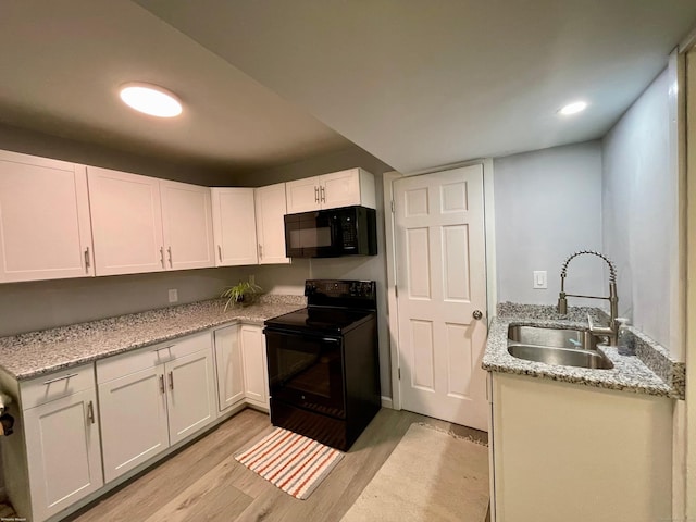 kitchen with light stone countertops, sink, light hardwood / wood-style floors, white cabinets, and black appliances