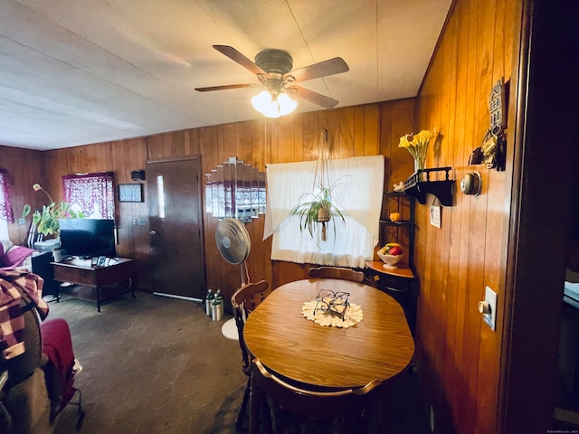 dining space featuring wood walls and ceiling fan