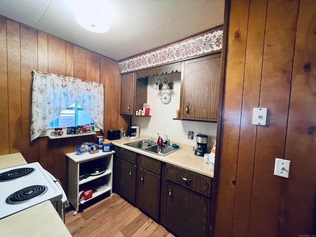 kitchen with white electric range, sink, wooden walls, and light hardwood / wood-style flooring