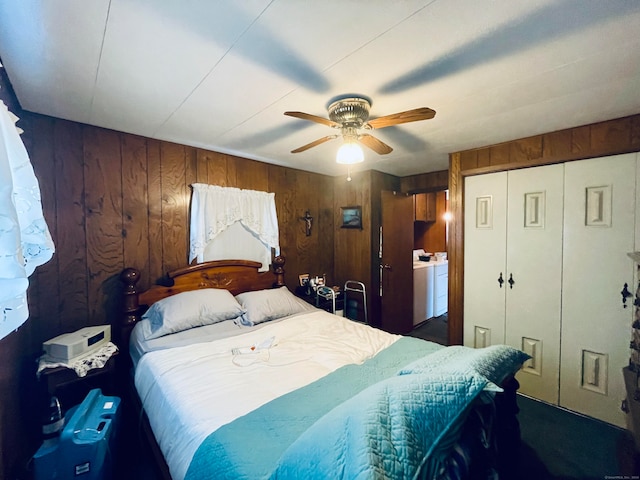 bedroom featuring wood walls, dark carpet, washing machine and clothes dryer, ceiling fan, and a closet