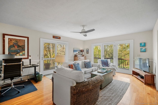 living room featuring plenty of natural light, ceiling fan, a textured ceiling, and light hardwood / wood-style flooring