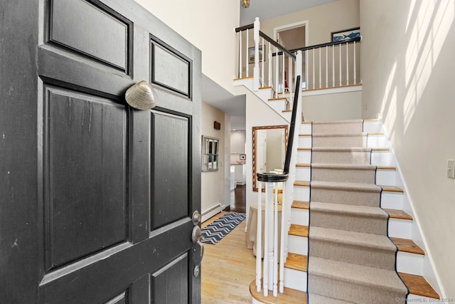 stairs with hardwood / wood-style floors and a baseboard heating unit