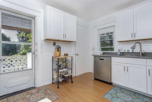 kitchen with light hardwood / wood-style floors, white cabinets, stainless steel dishwasher, and sink