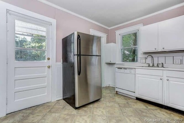 kitchen featuring dishwasher, ornamental molding, sink, white cabinets, and stainless steel refrigerator